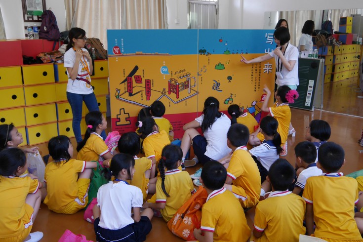 <p>The tutors are explaining the display of &ldquo;Writing&rdquo; to the students in Fengming Primary School. The display depicts the similarity between Chinese architecture and Chinese character: the former one is built by columns and beams, and the latter one is written by stokes.</p>